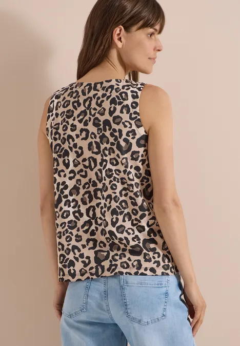 Frau von hinten in ärmellosem Top mit Leopardenmuster und Jeans.