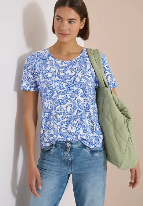 T-Shirt mit Rundhals und Muster vanilla white Frau trägt blau-weiß gemustertes Shirt, Jeans und grüne gesteppte Tasche.
