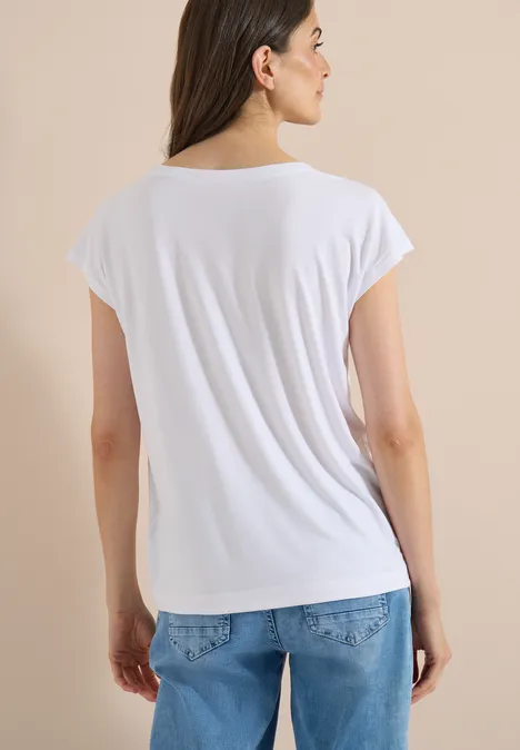 T-shirt à épaules tombantes avec découpe White Personne vue de dos portant un t-shirt blanc et un jean bleu sur fond beige.