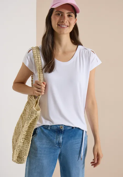 T-shirt à épaules tombantes avec découpe White Femme en T-shirt blanc, jean bleu, casquette rose, portant un sac en paille.