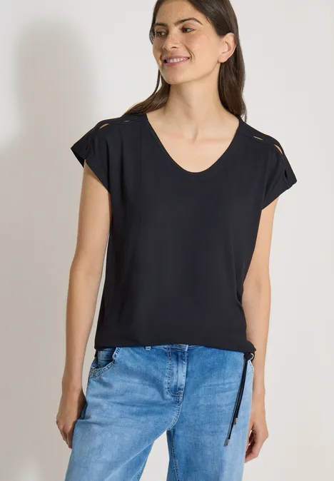 T-shirt à épaules tombantes avec découpe Black Femme portant un t-shirt noir à col en V et manches courtes avec jeans bleus.