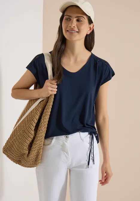 T-shirt à épaules tombantes avec découpe universal blue Femme en t-shirt bleu marine, pantalon blanc, sac en paille et casquette