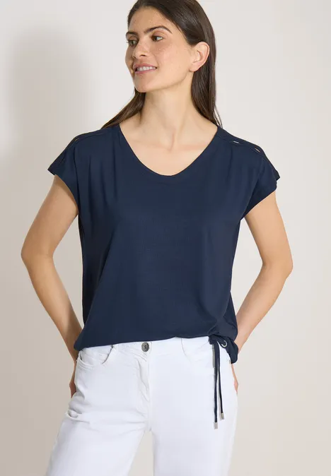T-shirt à épaules tombantes avec découpe universal blue Femme en t-shirt bleu marine à manches courtes et pantalon blanc.