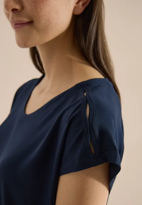 T-shirt à épaules tombantes avec découpe universal blue Une femme porte un haut bleu marine à manches courtes avec une fente et un détail noué à l'épaule.