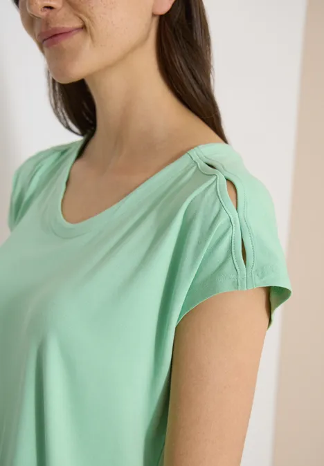 T-shirt à épaules tombantes avec découpe juicy lime Gros plan d'une personne en T-shirt vert menthe avec un détail torsadé à l'épaule.