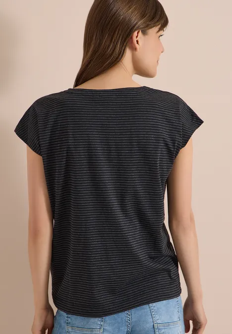 Vrouw van achteren in gestreept t-shirt en spijkerbroek voor lichte achtergrond.