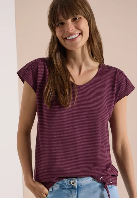 Vrouw in paarse gestreepte T-shirt tegen neutrale achtergrond.