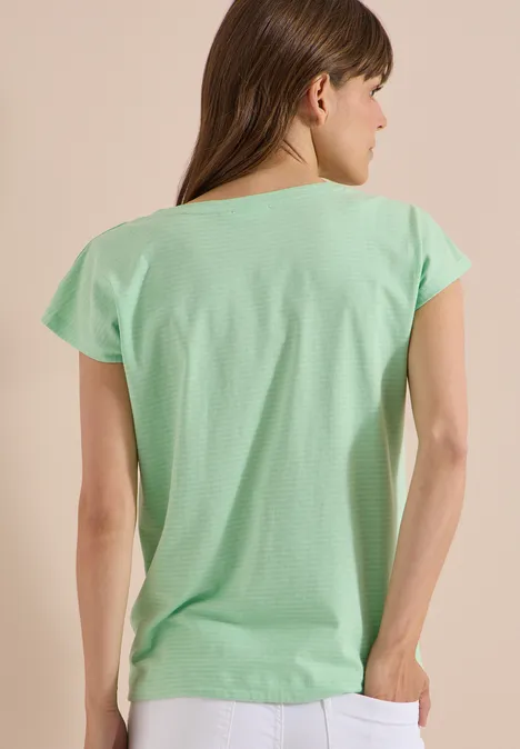 Eine Frau in einem mintgrünen T-Shirt, von hinten gezeigt.