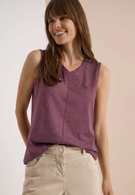 Top mit V-Neck und Streifen sweet grape red Eine Frau trägt ein lila ärmelloses Top und beige Hosen vor neutralem Hintergrund.