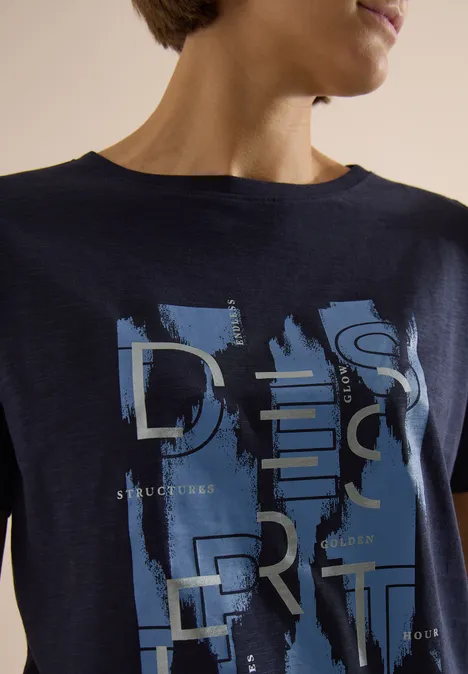 Dunkelblaues T-Shirt mit abstrakten Pinselstrichen und silbernen Lettern am Oberkörper.