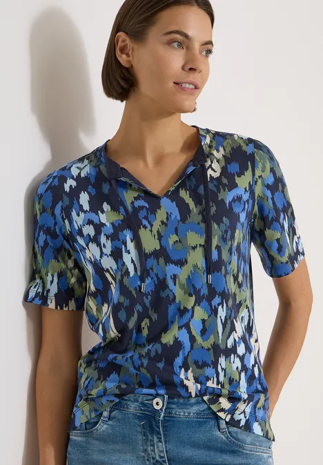 T-Shirt mit Split Neck und Print urban dark blue Person mit kurzärmligem Oberteil in abstraktem Blau-Grün-Print.