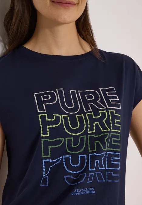 Frau trägt dunkelblaues T-Shirt mit dem Schriftzug 'PURE' viermal in Weiß, Grün und Blau.