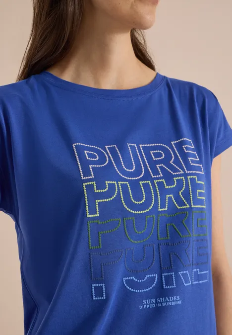 Eine Person trägt ein blaues T-Shirt mit dem aufgedruckten Schriftzug „PURE“ in verschiedenen Farbtönen.