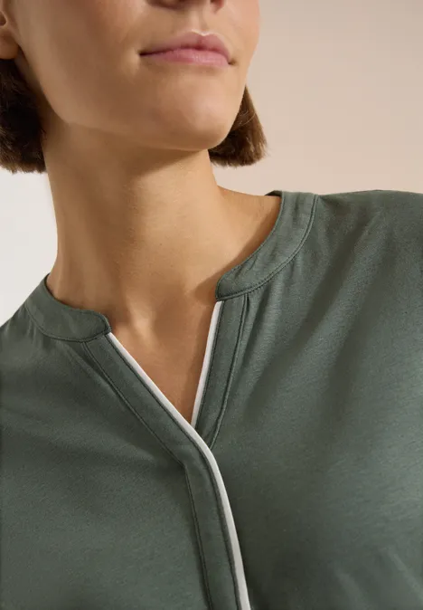T-Shirt mit Split Neck in Unifarbe dried olive green Nahe Aufnahme einer Frau in hellem Khaki-Shirt mit V-Ausschnitt und weißer Paspelierung.