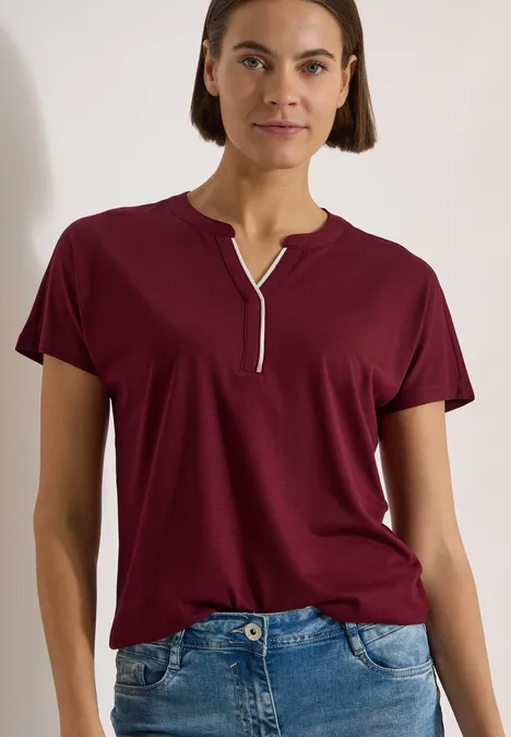 T-Shirt mit Split Neck in Unifarbe red wine Eine Frau trägt ein kurzärmeliges, burgunderrotes T-Shirt mit V-Ausschnitt und blaue Jeans.
