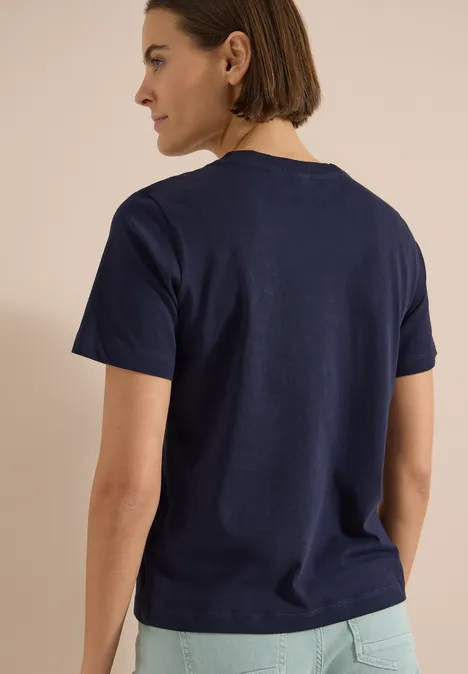 Person von hinten in dunkelblauem T-Shirt und hellen Hosen.