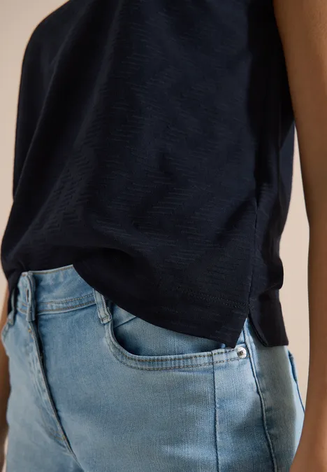 Shirt met boothals en structuur urban dark blue Zijaanzicht van persoon met donkerblauwe top en lichtblauwe spijkerbroek, gefocust op bovenlichaam.