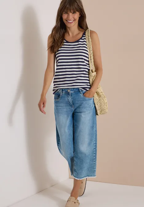 Top mit Rounded V-Neck und Streifen urban dark blue Junge Frau trägt gestreiftes Top, weite Jeans und Korbtasche, steht lächelnd an der Wand.