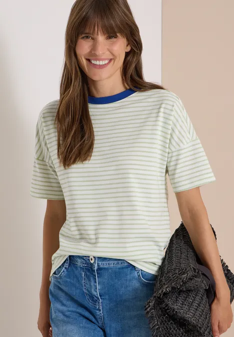 Eine lächelnde Frau in gestreiftem T-Shirt und blauen Jeans, die eine schwarze gewebte Tasche hält.