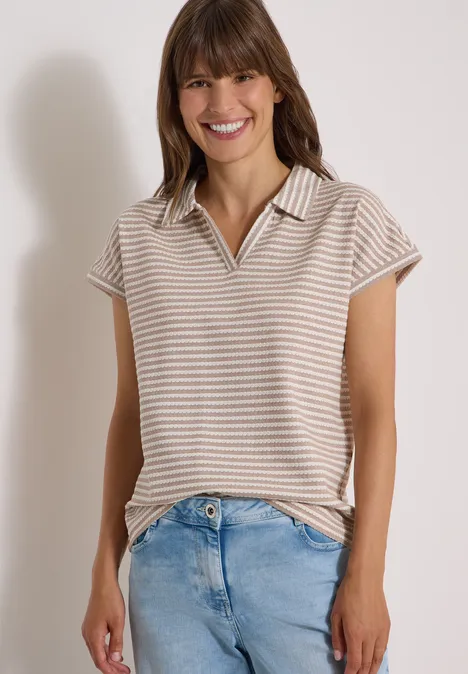 Poloshirt met korte mouwen en gestreept patroon creamy mocha Een glimlachende vrouw in een gestreept poloshirt en blauwe jeans.