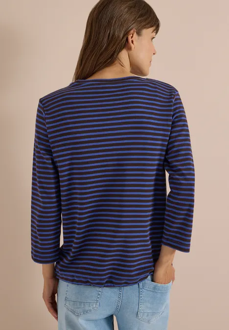 Rückenansicht einer Frau in blau-schwarz gestreiftem 3/4-Arm-Shirt und hellblauen Jeans.