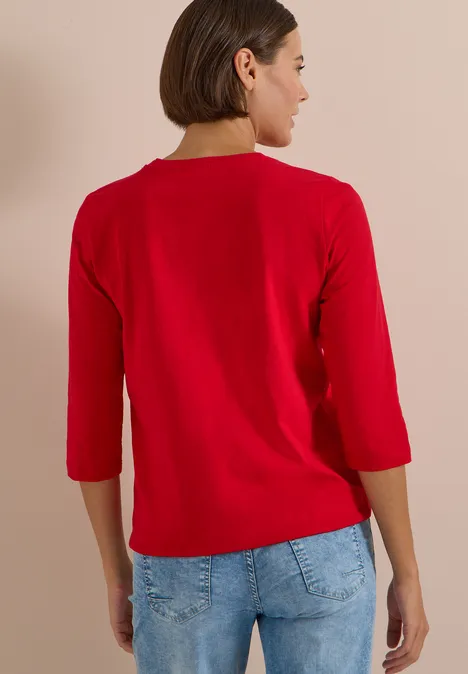 3/4-Arm Shirt mit Rundhals in Unifarbe flame red Frau in rotem Dreiviertelarm-Shirt, Jeans, Rückansicht, vor hellem Hintergrund.