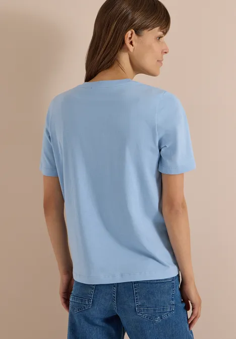 Shirt met luipaardprint en folie-details easy blue Frau von hinten in hellblauem T-Shirt und Jeans vor neutralem Hintergrund.