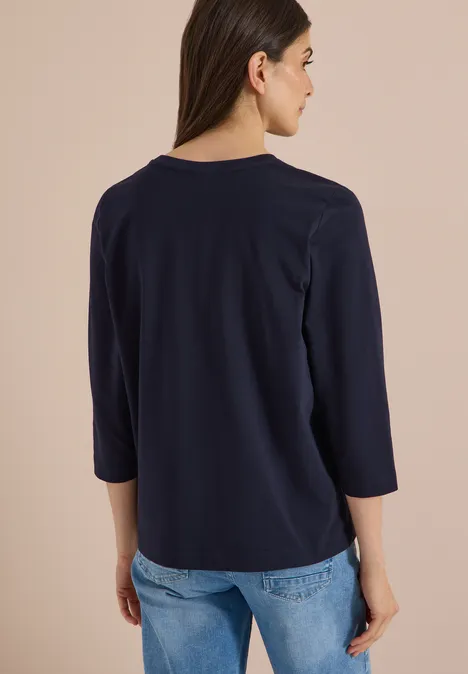 Koszulka z rękawami 3/4 z napisem w stylu lampartowym urban dark blue Widok z tyłu na kobietę w granatowej bluzce 3/4 rękaw i jasnoniebieskich dżinsach.