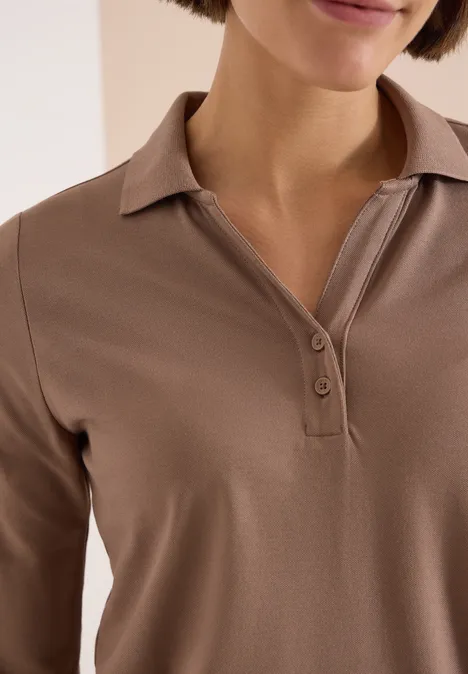 Nahaufnahme einer Person in braunem Poloshirt mit offenem Kragen und Knopfleiste.