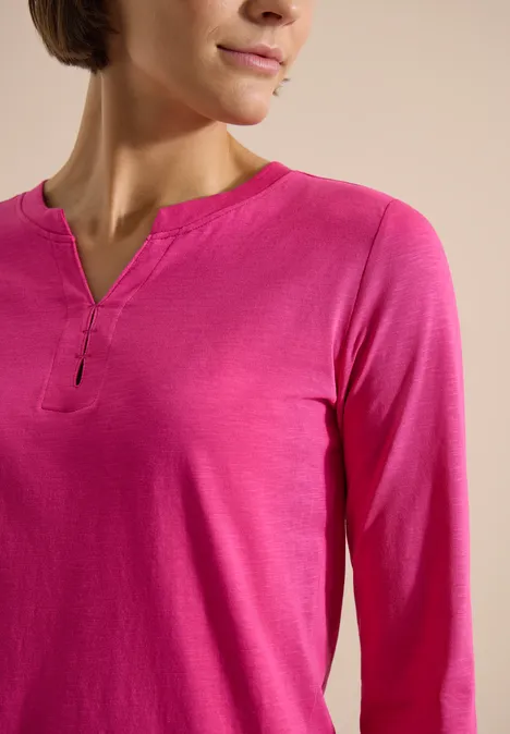 Damen-Oberteil in knalligem Pink mit langen Ärmeln und kleinem V-Ausschnitt.