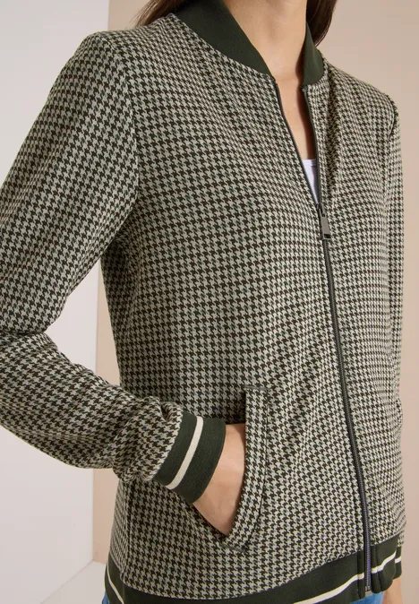 Damen-Bomberjacke mit grün-schwarzem Hahnentrittmuster, Reißverschluss und gestreiften Strickbündchen.