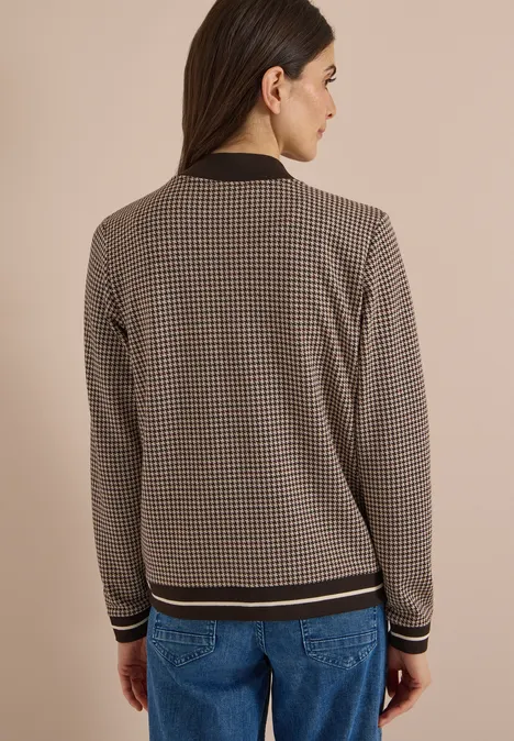 Rückansicht einer Frau in Jeans und kariertem, tailliertem Strickcardigan mit kontrastierenden Bündchen.