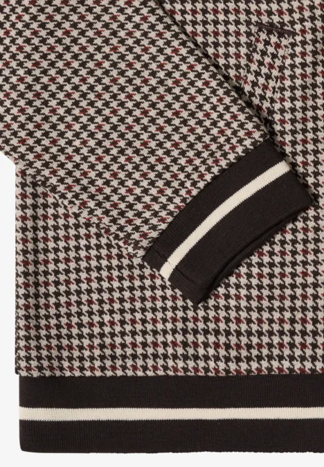 Nahaufnahme eines Pullovers mit Hahnentritt-Muster in Schwarz, Weiß und Rot, gerippter Saum mit weißen Streifen.