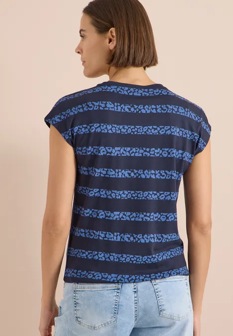 Rückenansicht einer Frau in blau-schwarz gestreiftem Kurzarmshirt und heller Jeans.