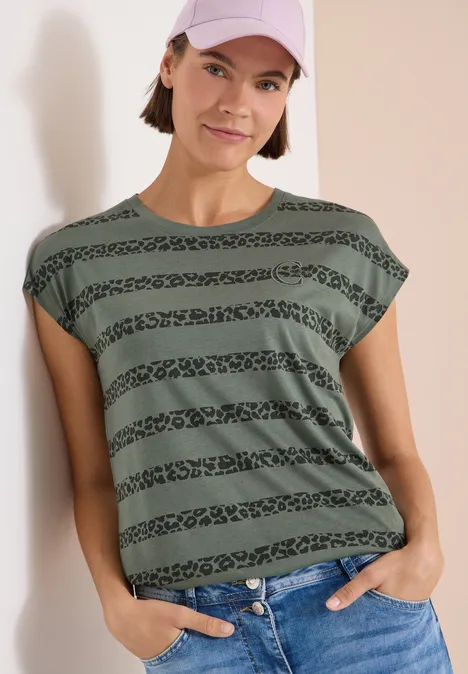 Frau trägt grünes T-Shirt mit horizontalen Tiermuster-Streifen, kurze überschnittene Ärmel.