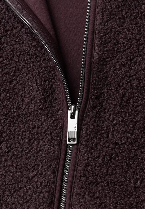 Nahaufnahme einer dunkelbraunen Sherpa-Fleecejacke mit glänzendem Metallreißverschluss.