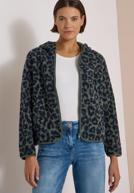 Lockere Fleece-Bomberjacke im Leopardenmuster mit Reißverschluss, passend zu weißem Top und Jeans.