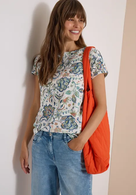 Vrouw lacht, draagt een gemêleerd T-shirt, spijkerbroek en een oranje schoudertas.