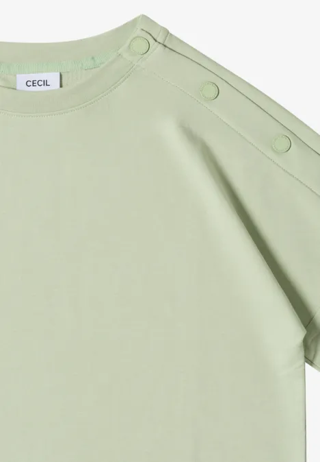 T-shirt vert pastel avec rabat asymétrique à l’épaule et trois boutons-pression