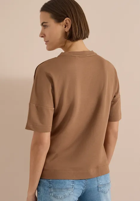 Vue arrière d'une femme portant un haut marron à manches courtes et un jean bleu