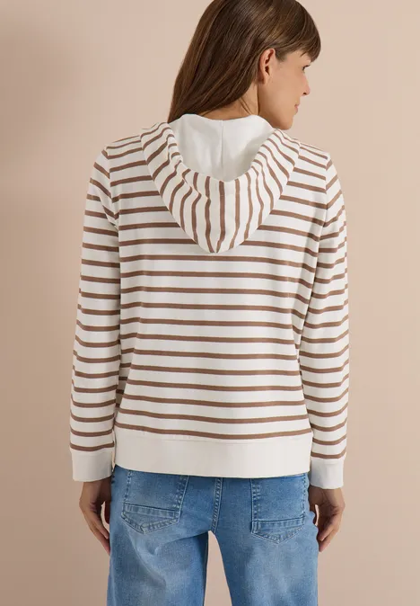 Frau von hinten in gestreiftem Kapuzenpullover (weiß-beige) und blauen Jeans.