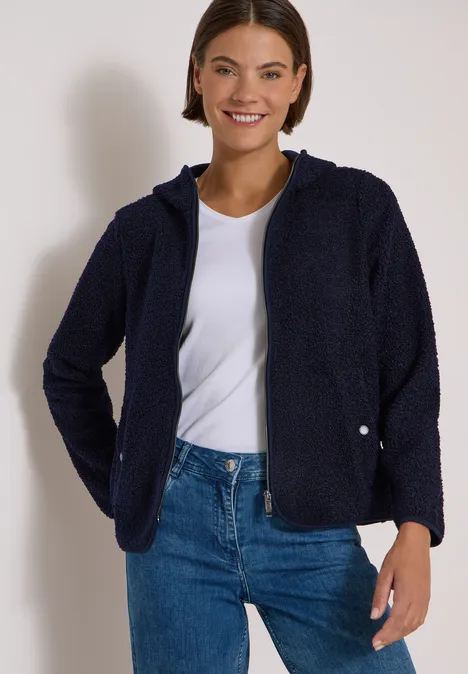 Teddy-Jacke mit Kapuze in Unifarbe urban dark blue Lächelnde Frau in dunkelblauer Fleecejacke, weißem T-Shirt und Jeans vor hellem Hintergrund.