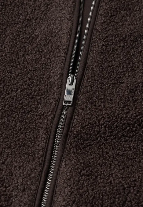 Close-up van een zilveren rits op bruin fleece.