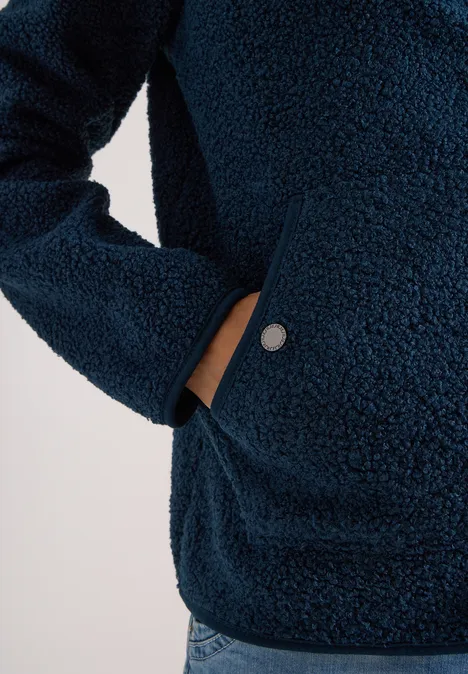 Dunkelblaue Teddy-Fleecejacke mit Eingrifftasche, weiche Struktur und silberner Druckknopf am Saum.