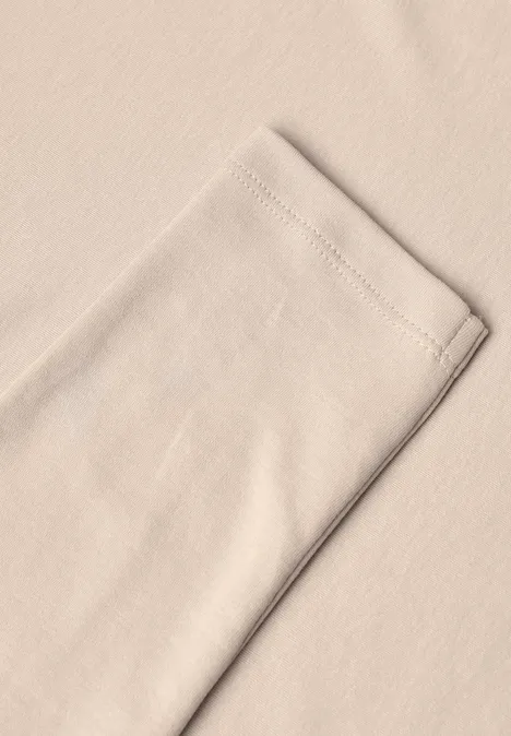 Langarm Shirt in Unifarbe mit V-Neck cashmere beige Nahe Aufnahme eines beigen Baumwollstücks mit sichtbarer Saumnaht am Rand.
