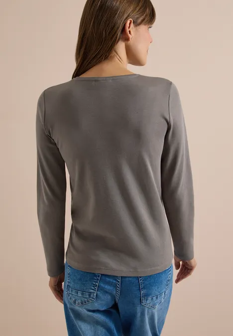 Langarm Shirt in Unifarbe mit V-Neck storm grey Frau von hinten in grauem Langarmshirt und blauen Jeans vor neutralem Hintergrund.