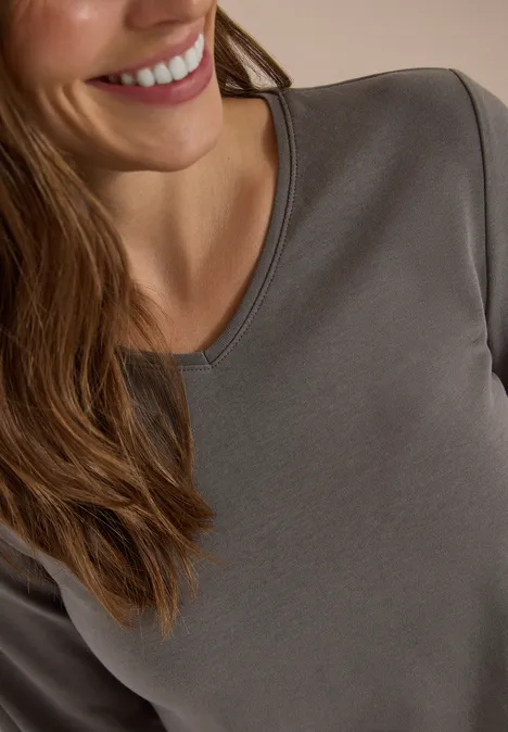 Langarm Shirt in Unifarbe mit V-Neck storm grey Nahaufnahme einer lächelnden Frau in einem grauen Langarmshirt.