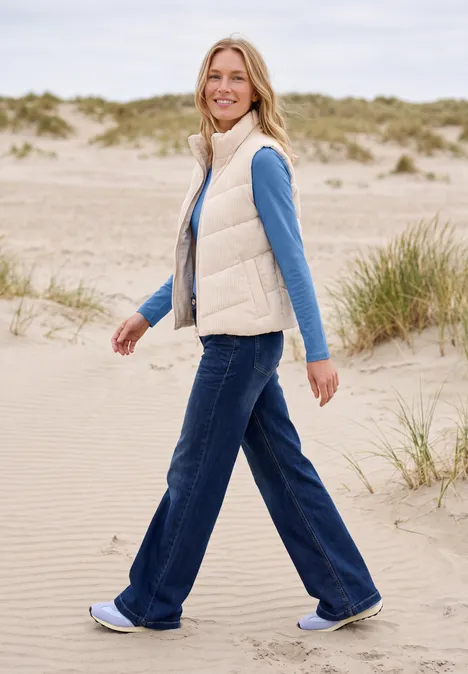 Langarm Shirt in Unifarbe mit V-Neck north blue Eine Frau in Weste, Jeans und Turnschuhen spaziert über Sanddünen am Strand.