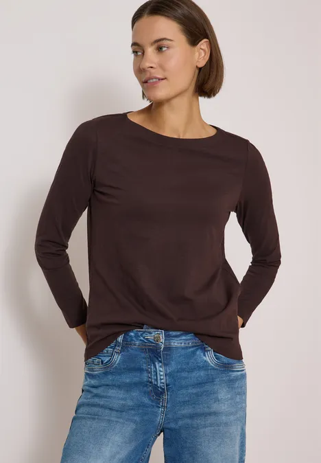 Langarm Shirt mit U-Boot-Ausschnitt truffle brown Frau in braunem Langarmshirt und blauen Jeans steht vor neutralem Hintergrund.