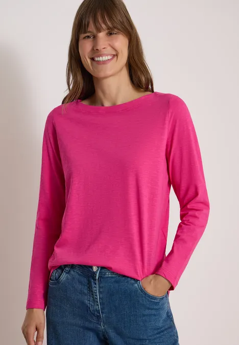 Langarm Shirt mit U-Boot-Ausschnitt pink flash Eine Frau lächelt und trägt einen knallpinken Pullover mit langen Ärmeln und blauen Jeans.